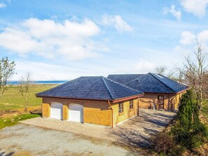 A two-story brick building with a tiled roof, a garage, and a driveway. - 5 Star Holiday Home in Hojslev (Hojslev)