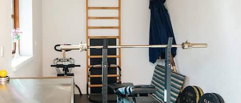 A home gym with a bench press, a squat rack, a pull-up bar, and weight plates.