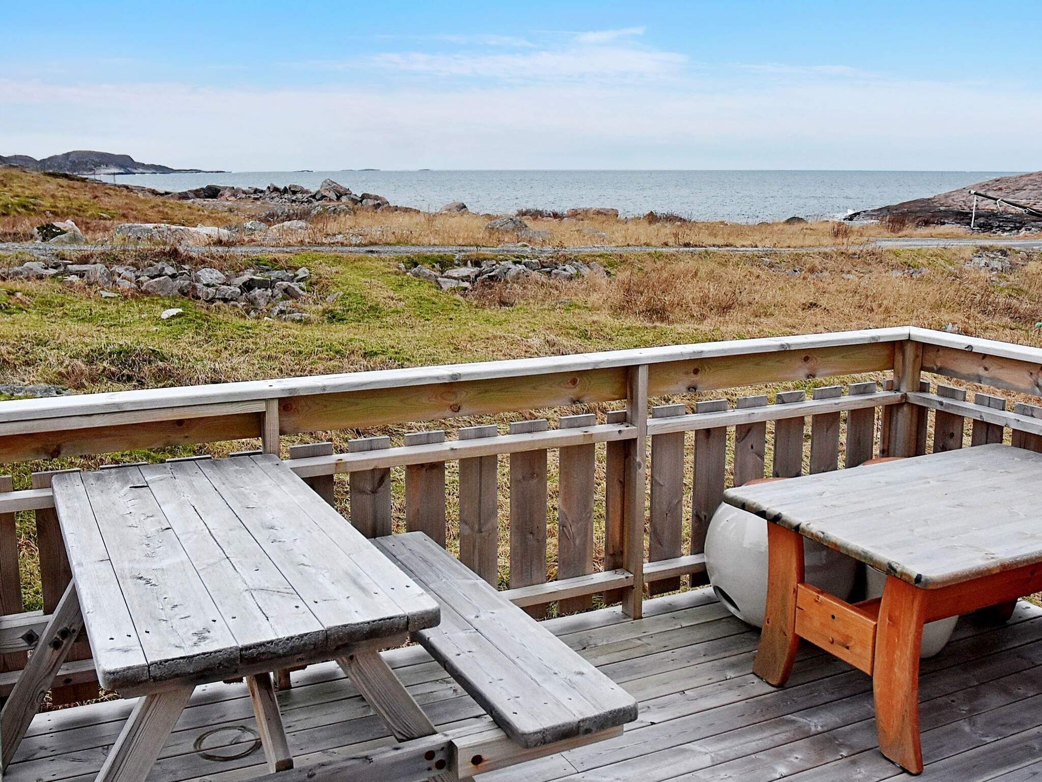Un pontile in legno con tavoli da picnic e vista sul mare.