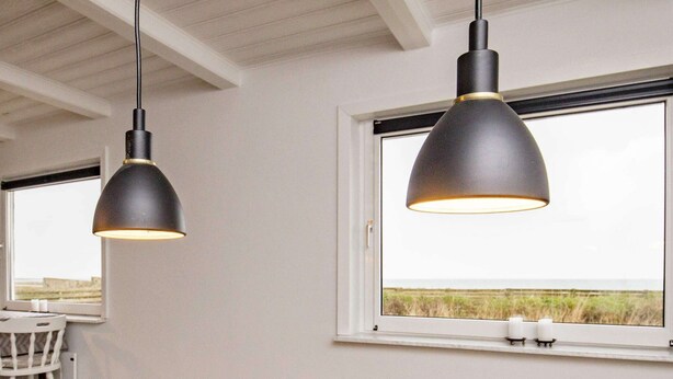 A modern room with two pendant lights, a white radiator, and a view of the outdoors through a large window. - Holiday Home in Hurup Thy (Hurup Thy)
