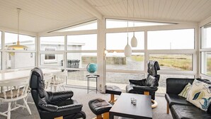 A modern room with a large window, a white desk, black leather chairs, and a black leather sofa. - Holiday Home in Hurup Thy (Hurup Thy)