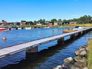A pier extending over calm water with boats docked, surrounded by houses and greenery. - 4 Person Holiday Home in Hemse (Hemse)