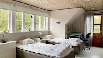 A bedroom with two beds, a desk, a chair, and a window with curtains.