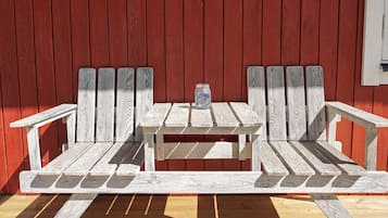 A wooden bench with a table in front of a red wooden wall.