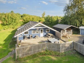 A blue cabin with a deck, a barbecue area, and a small shed. - 4 Star Holiday Home in Sydals (Sydals)