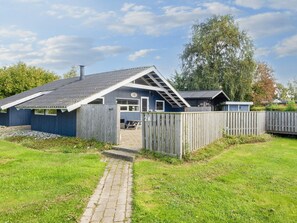 A blue building with a sloped roof, a wooden fence, and a paved pathway leading to the entrance. - 4 Star Holiday Home in Sydals (Sydals)