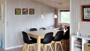 A dining area with a wooden table and black chairs, wooden panel walls, and a bookshelf with books. - 6 Person Holiday Home in Fano (Fano)