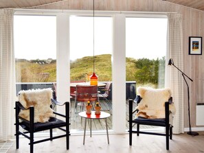 A room with two chairs, a table, and a view through large glass doors. - 6 Person Holiday Home in Fano (Fano)