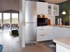A modern kitchen with white cabinetry, a built-in oven, and a coffee machine.