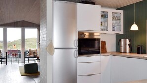 A modern kitchen with white cabinets, a built-in oven, and a coffee machine. - 6 Person Holiday Home in Fano (Fano)