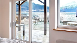 A bedroom with a large sliding glass door leading to an outdoor deck with a view of a lake and mountains. - 6 Person Holiday Home in Eidsvag (Molde)