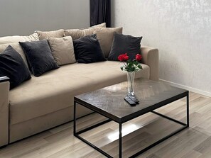 A living room with a sofa, a coffee table, and a vase with flowers.