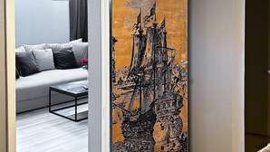 A room with a grey sofa, a coffee table, and a large black and orange artwork depicting a ship. - 6 Person Holiday Home in Visby (Visby)