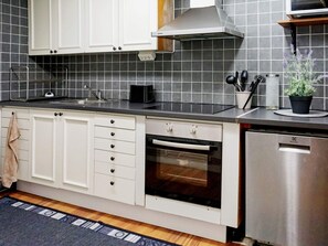 A kitchen with white cabinets, a stainless steel dishwasher, and a black countertop. - 6 Person Holiday Home in Visby (Visby)