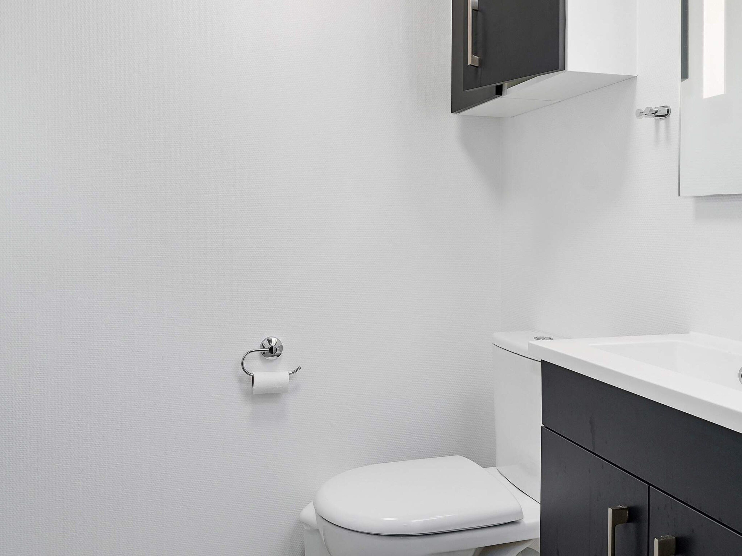 A modern bathroom with a toilet, a sink, and a cabinet.