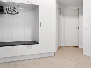 A white wardrobe with a black countertop, a hanging rack, and a door leading to another room. - Holiday Home in Kappeln (Kappeln)