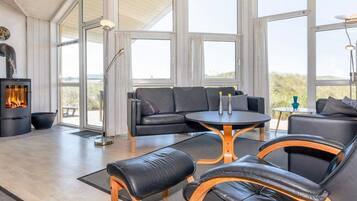 A modern living room with a fireplace, leather furniture, and large windows.