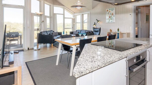 A spacious living area with a large kitchen island, a dining table, and a seating area with sofas.