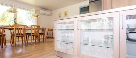 Une cuisine moderne avec des meubles en bois, un coin repas avec des chaises en bois et des luminaires suspendus.