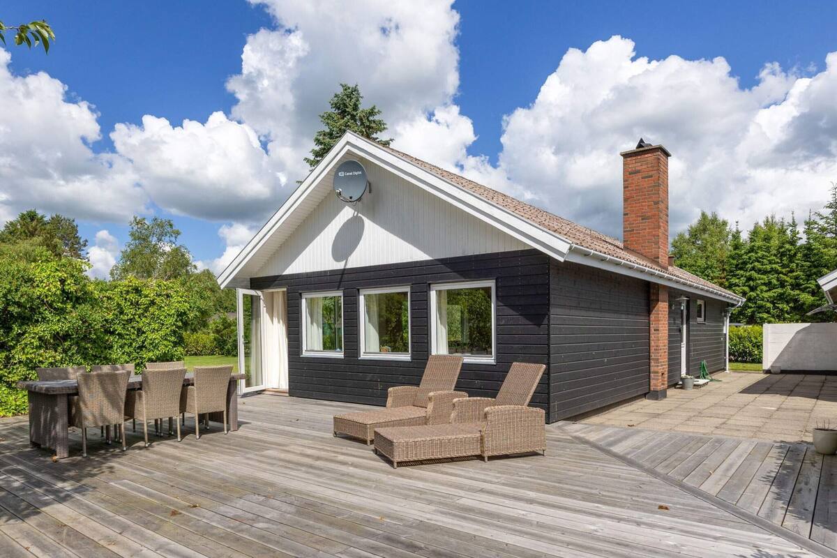 A modern house with a deck, a chimney, and a satellite dish.