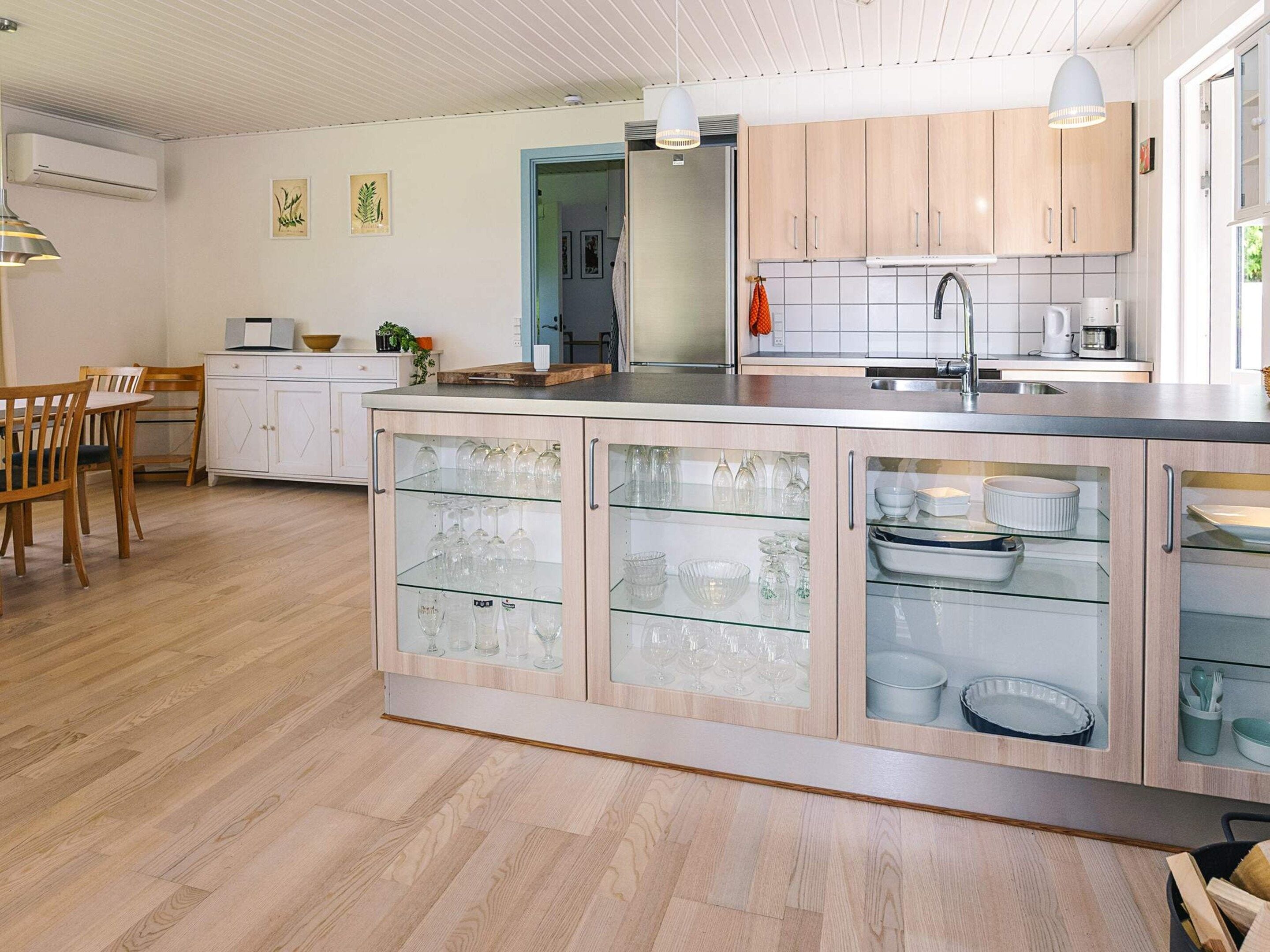 Une cuisine moderne dotée d’un îlot central, de meubles en bois et d’un coin repas avec une table et des chaises.