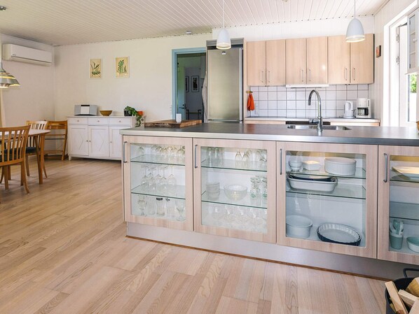 A modern kitchen with a central island, wooden cabinets, and a dining area with a table and chairs.