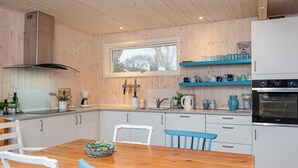 Eine moderne Küche mit Holzschränken, einem Esstisch, Stühlen und einem Siemens-Ofen.