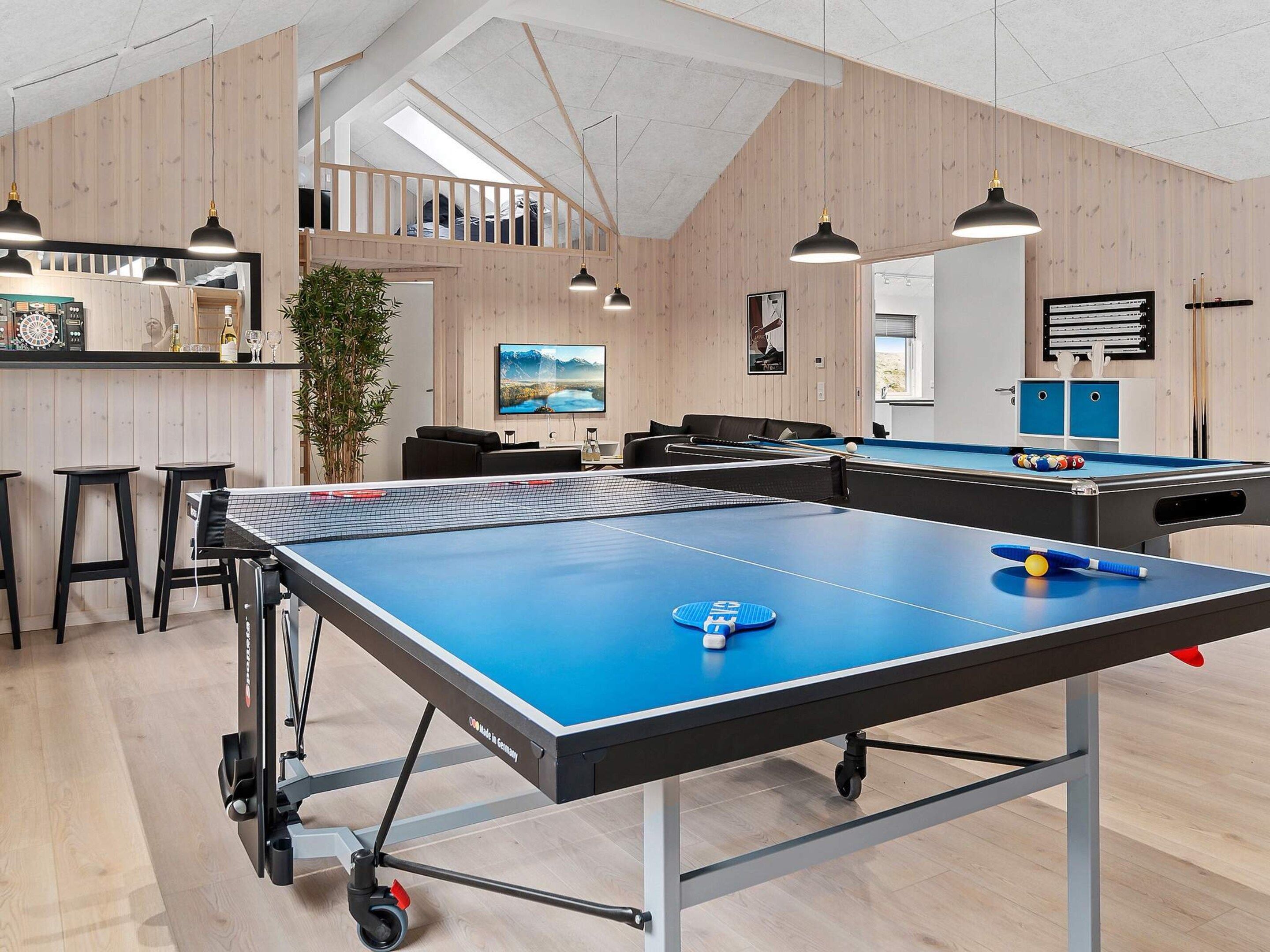 Una mesa de ping pong en una habitación con paredes de madera y una zona en alto.