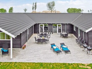A covered patio area with outdoor seating and lounge chairs. - Holiday Home in Kappeln (Kappeln)