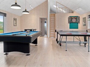 A modern indoor recreational area with a pool table, a ping pong table, and a dartboard.