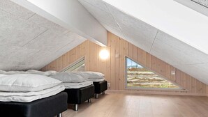A modern attic bedroom with a sloped ceiling, wooden walls, and a large skylight. - Holiday Home in Kappeln (Kappeln)