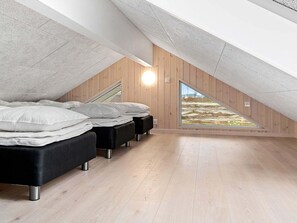 A modern attic bedroom with a sloped ceiling, wooden walls, and a large skylight. - Holiday Home in Kappeln (Kappeln)