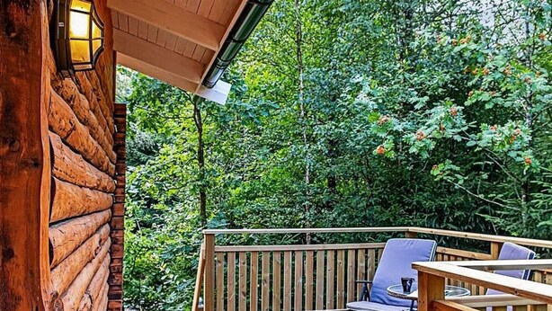 Une terrasse en bois avec une rambarde, une chaise et une table.