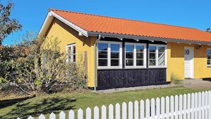 A yellow building with a red roof, white windows, and a white picket fence in front. - 7 Person Holiday Home in Skagen (Skagen)