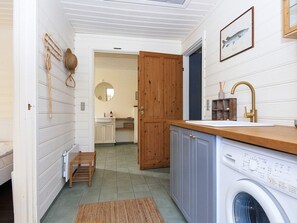Ein kleiner Hauswirtschaftsraum mit Waschmaschine, Holzausbau und Spüle.