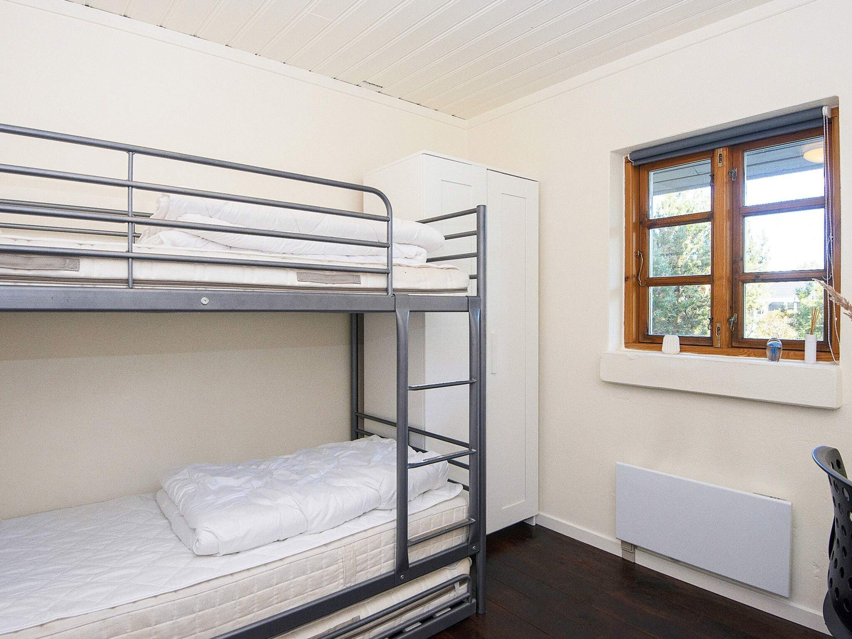 A bunk bed room with a window and radiator.