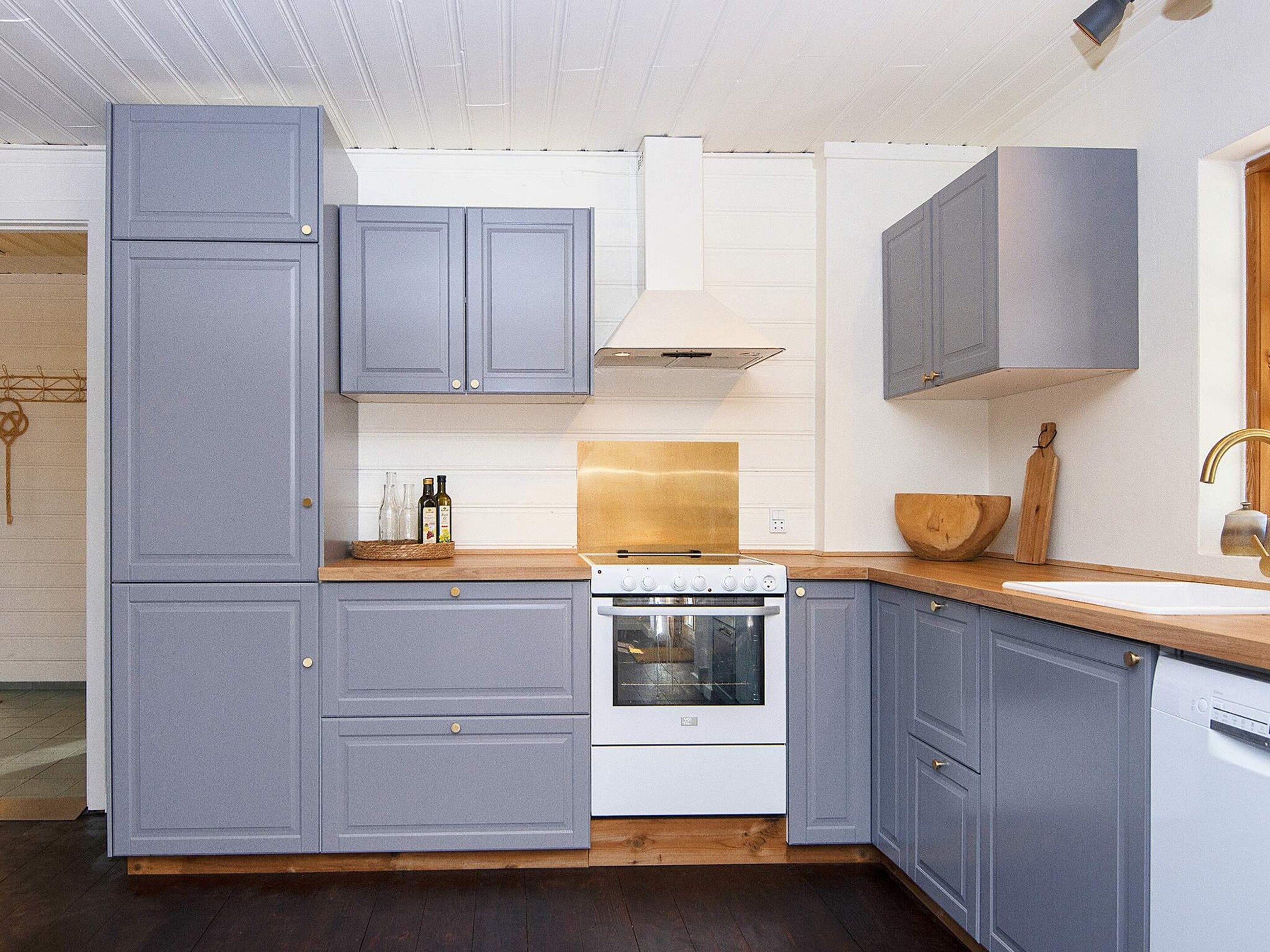 Una cocina moderna con armarios grises, una estufa blanca y una encimera de madera.