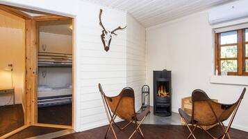 Una habitación acogedora con chimenea, dos sillones de cuero, una cama con cabecero de madera y una decoración de cráneo de venado en la pared.
