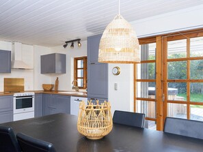 A modern kitchen with grey cabinets, a wooden countertop, and a hanging wicker light fixture.