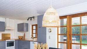 Une cuisine moderne avec des meubles gris, une table en bois et un luminaire suspendu en osier.