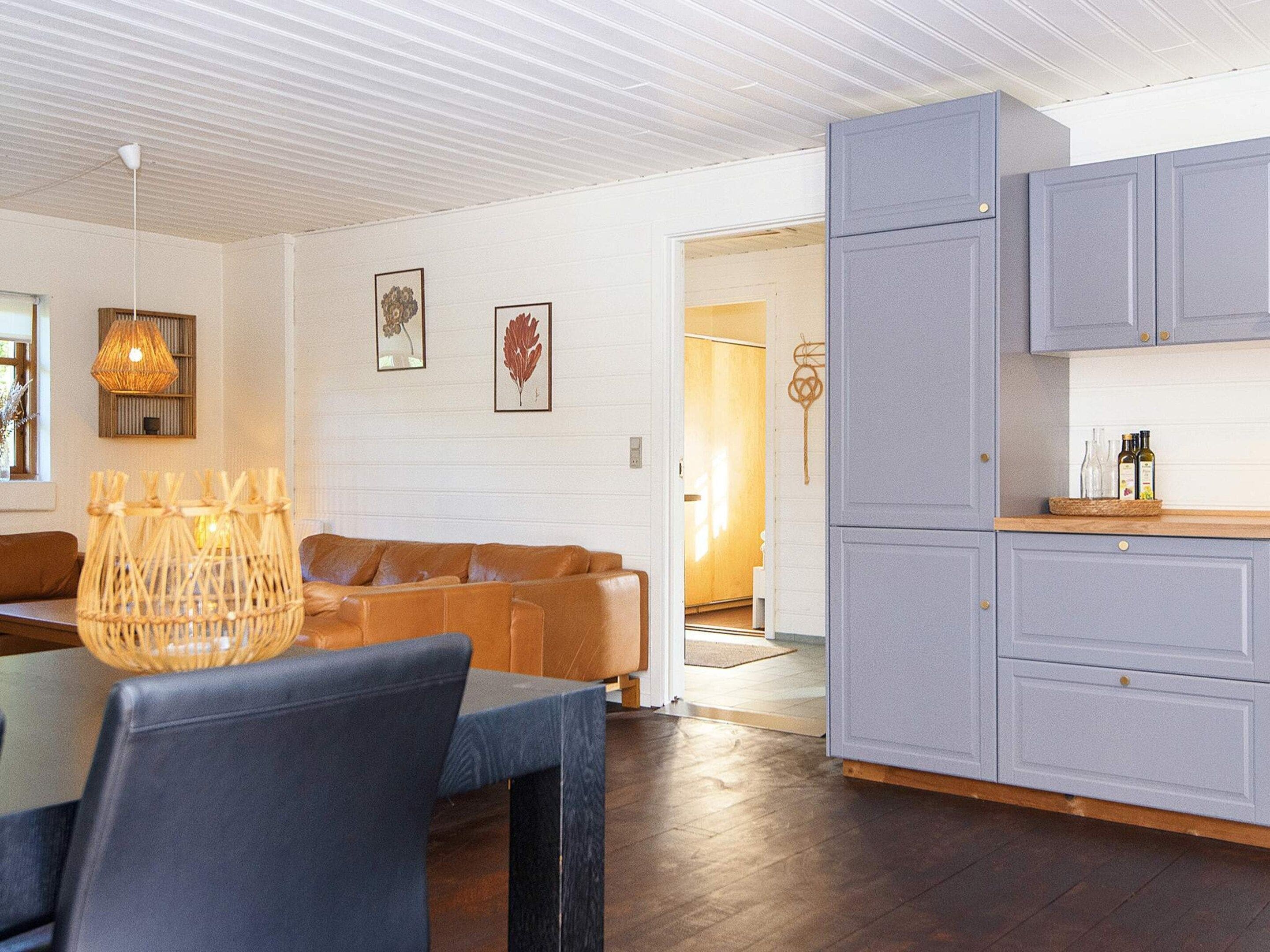 A modern kitchen with grey cabinets, a dining area with a table and chairs, and a living room with a sofa and decorative wall art.