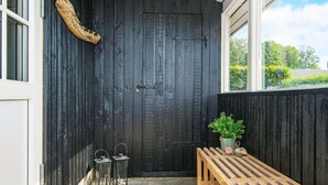 Un banc en bois et deux lanternes se trouvent devant une porte noire.