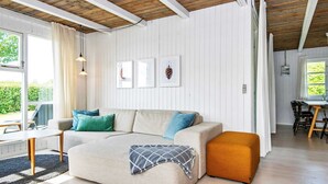 Un salon moderne avec un canapé, un pouf et un coin repas.
