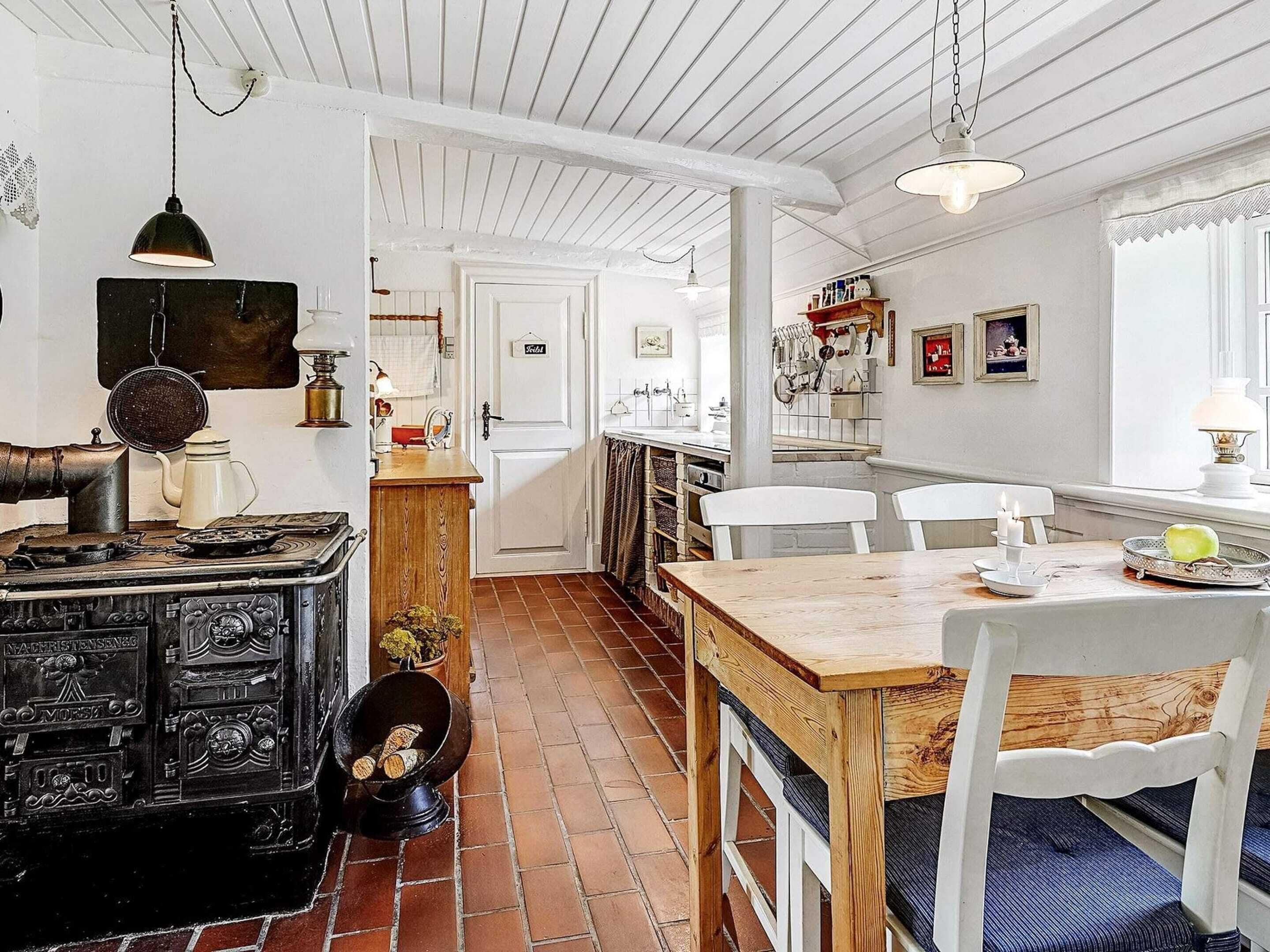 A kitchen with a stove, chairs, and a dining table.