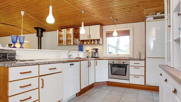 A modern kitchen with white cabinets, a built-in oven, and a large window. - 6 Person Holiday Home in Dannemare (Dannemare)