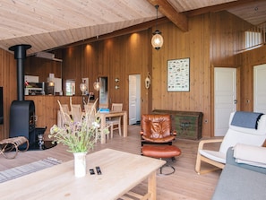 A wooden interior with a dining area, a fireplace, and a seating area with a bench and chairs.