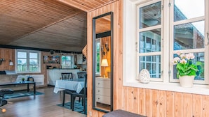 En mysig stuga med en matplats, en bänk och ett kök som syns genom en öppen dörr.