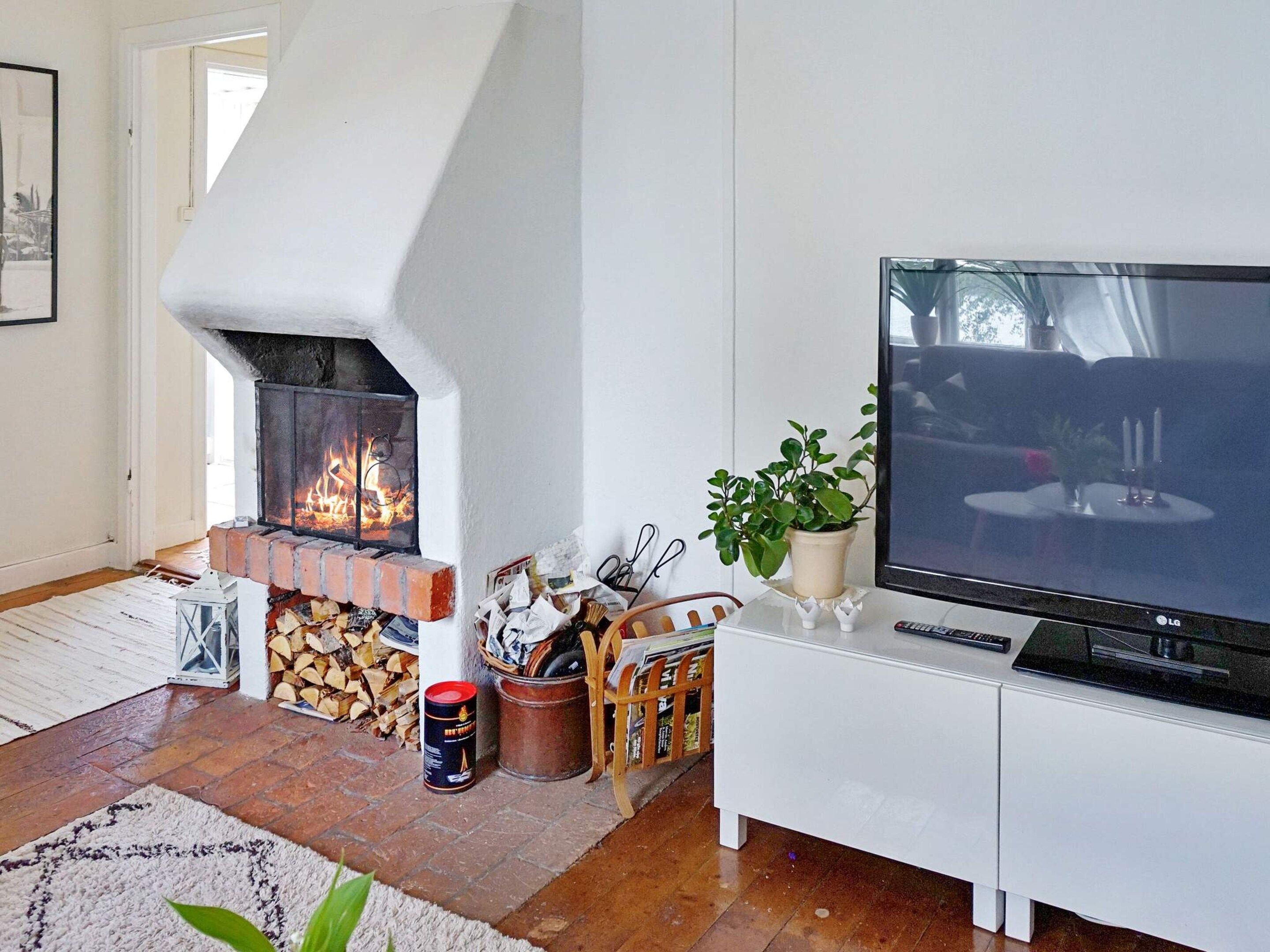 A living room with a fireplace, a television, and a potted plant.
