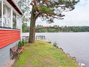 A lakeside property with a red building, a dock, a boat, and a tree.