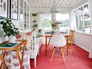 A cozy room with a wooden dining table, white chairs, a red carpet, and a white bench. - 5 Person Holiday Home in Akersberga (Akersberga)